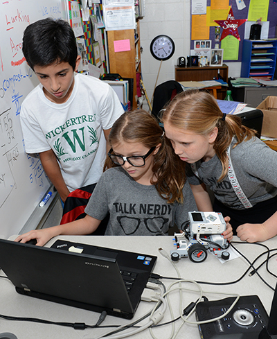 Elementary School students programming a small wheeled robot